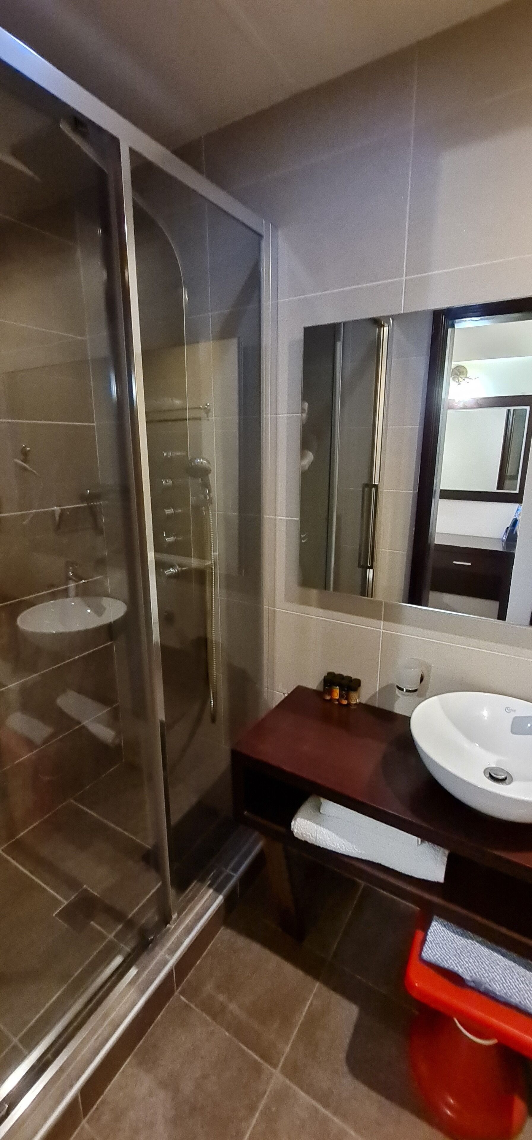 A modern bathroom with a glass-enclosed shower, a white sink, and a large mirror.