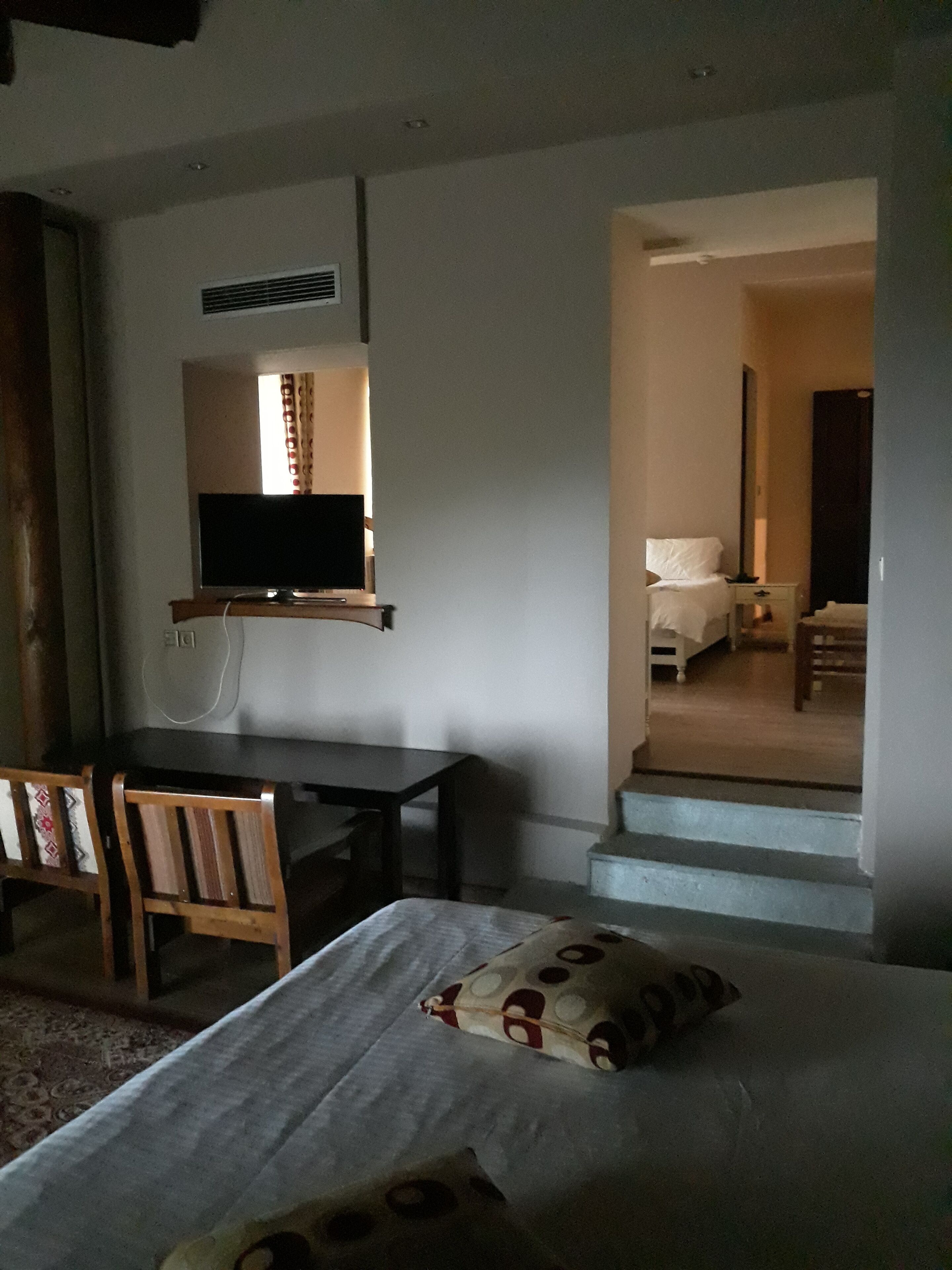 Ett hotellrum med en säng, ett skrivbord, en stol, en tv och en trappa som leder till ett annat rum.