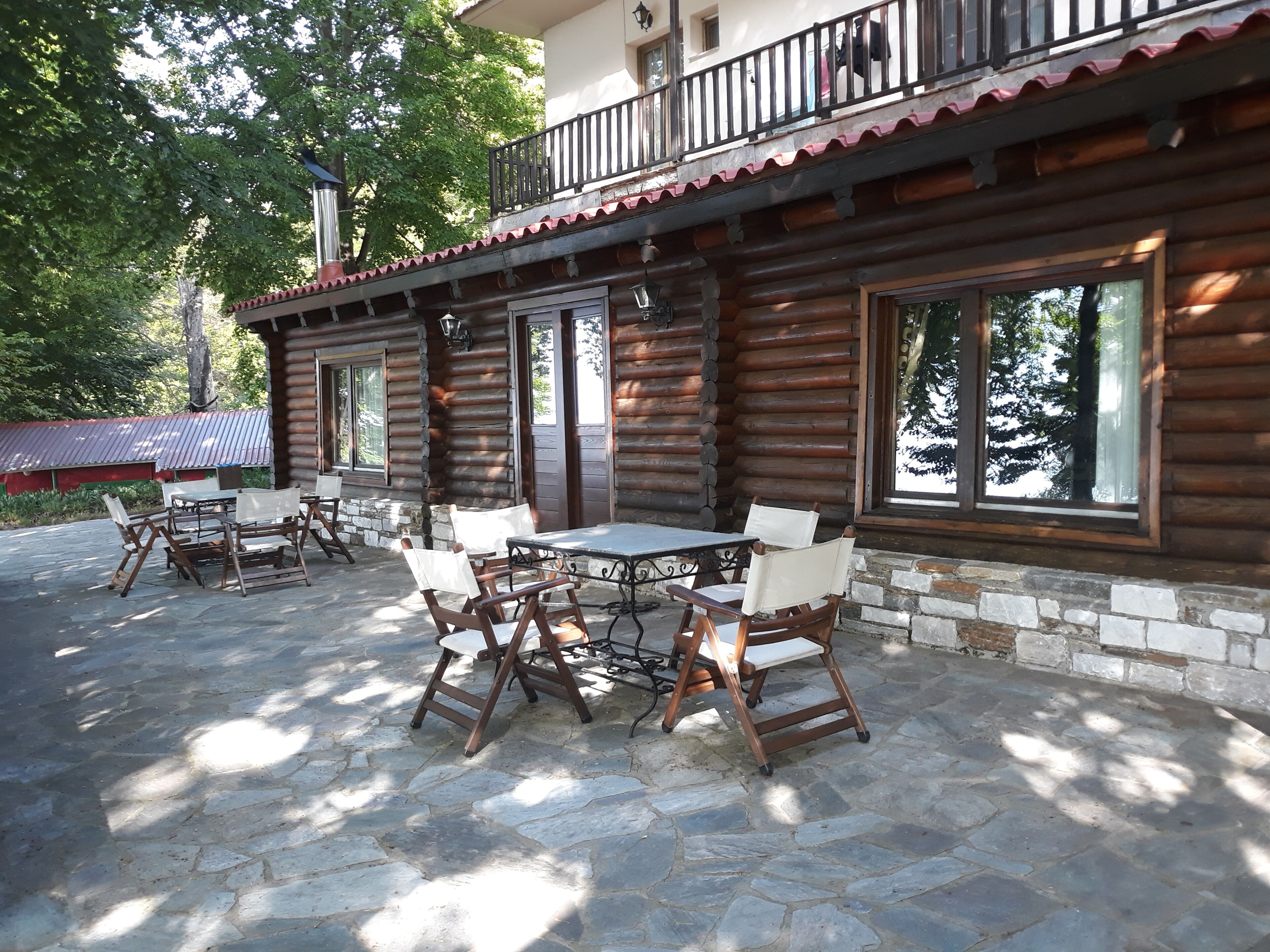 A log cabin with a balcony, stone flooring, and outdoor seating area.