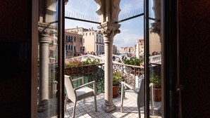 Un balcon avec des fauteuils en osier, une plante en pot et une vue sur un paysage urbain avec des bâtiments et un pont.