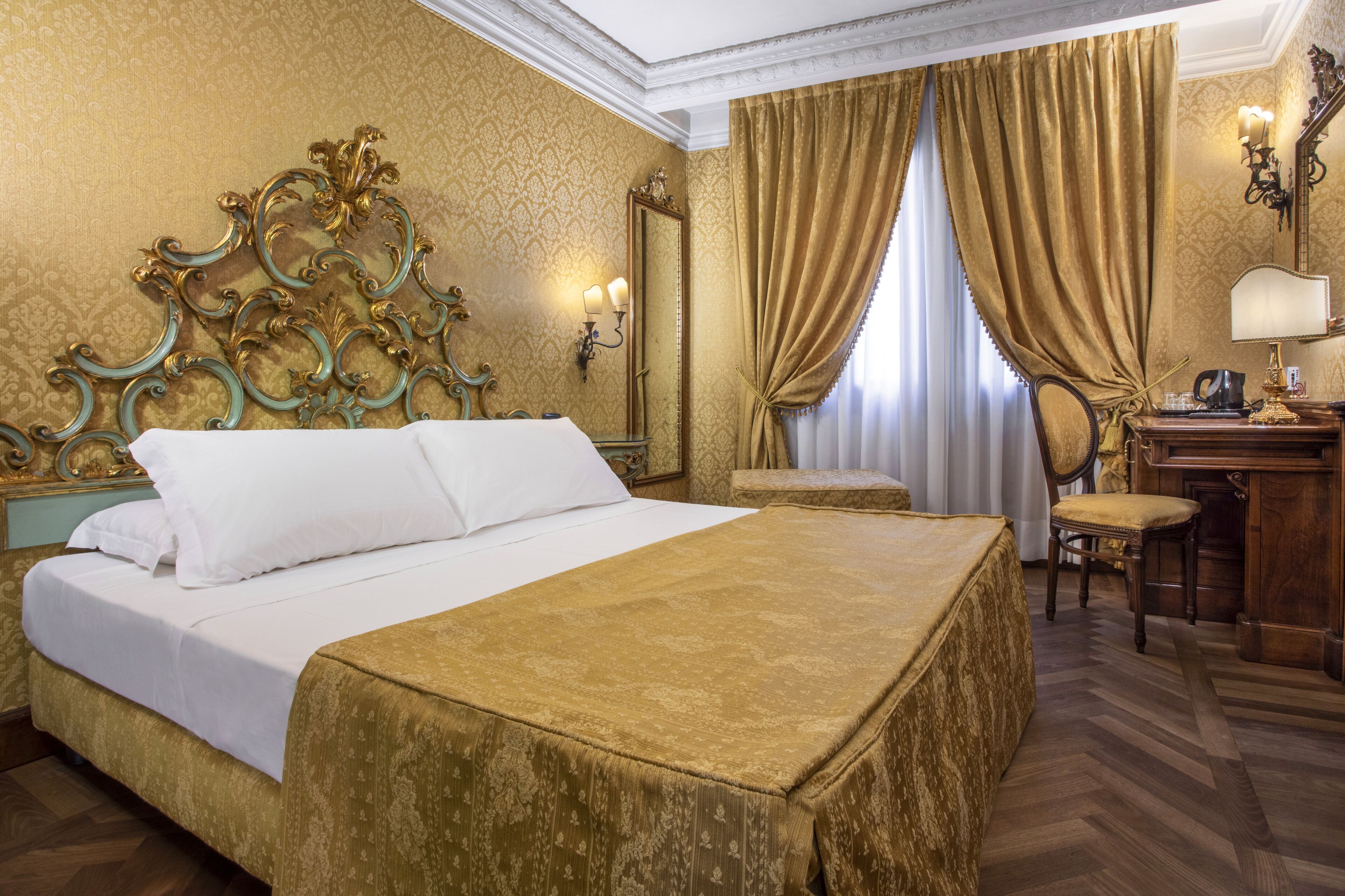 Ein Hotelzimmer mit einem großen Bett, einem Schreibtisch mit Lampe, einem Sessel und einem Spiegel.