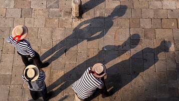 Two people from a top-down perspective, wearing striped shirts and straw hats, standing on a brick pavement.