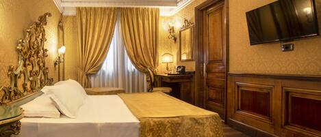 Un grand lit avec une tête de lit, une table de chevet, un miroir, un téléviseur fixé au mur et une fenêtre avec des rideaux.