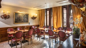 Un espace repas avec une longue table, de nombreuses chaises et un lustre.