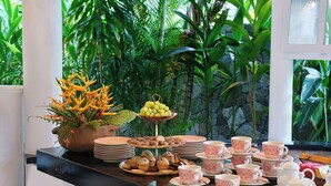 A tropical-themed buffet setup with a variety of food items and decorative plants. - East Winds Saint Lucia (Gros Islet)