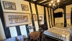 A traditional room with a bed, a wooden chair, a small table, and a desk. There are framed pictures on the walls. - The Bridge Street Historic Guest House (Sudbury)