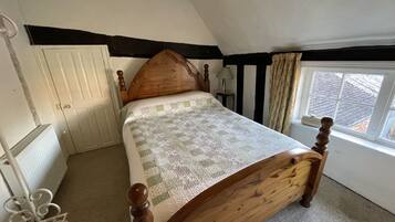 A bedroom with a wooden bed, a window with a view, a radiator, and a door.