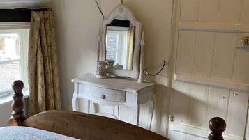 Un dormitorio con cama, cómoda, espejo, televisor montado en la pared y una puerta.