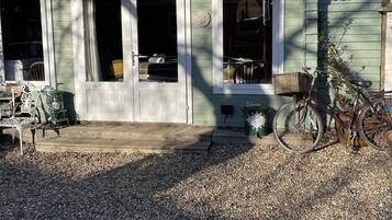 Een huis met een veranda, een fiets en een bankje.