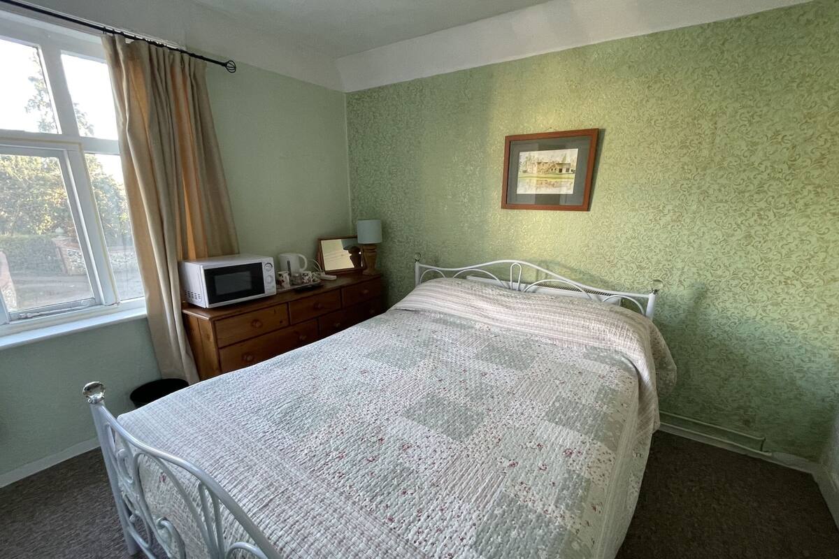 A bedroom with a bed, dresser, and a framed picture on the wall.