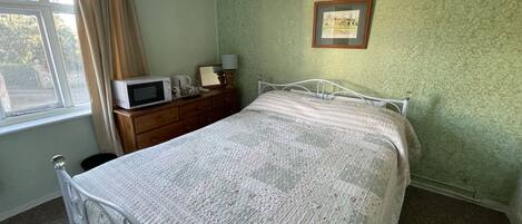 Une chambre à coucher avec un lit, une commode et un tableau encadré accroché au mur.