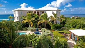 A two-story building with a pool and lush greenery.