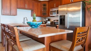 A kitchen with wooden cabinets, a stainless steel refrigerator, a microwave, and a dining area with a wooden table and chairs.