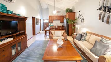 A spacious living room with a wooden coffee table, a sofa, and a television on a wooden cabinet.