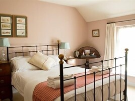 Un dormitorio con cama, mesitas de noche, un espejo y una ventana con cortinas.