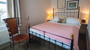 A neatly made bed with a striped bedspread, a chair with a cushioned seat, and two bedside lamps.