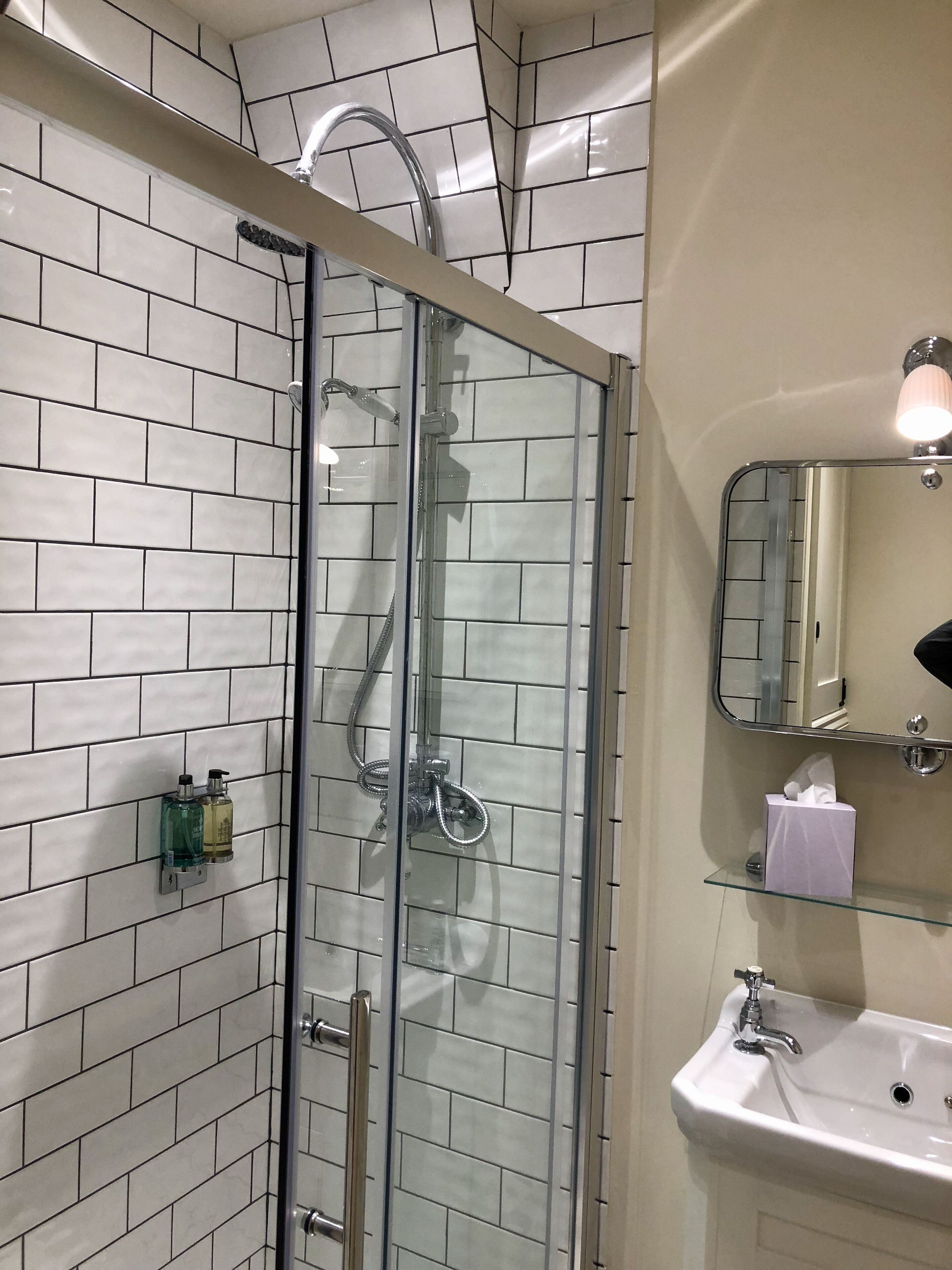 Un baño con ducha de vidrio, un lavabo blanco y un espejo sobre el lavabo.