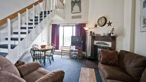 A living room with a staircase, a fireplace, and a dining area. - Silver Creek Lodge (Snowshoe)