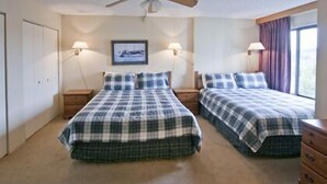 A bedroom with two beds, a ceiling fan, bedside lamps, a framed picture on the wall, and a window with curtains. - Silver Creek Lodge (Snowshoe)