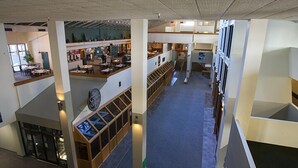 A multi-level indoor space with open areas and seating arrangements, featuring a staircase and a clock on the wall. - Silver Creek Lodge (Snowshoe)