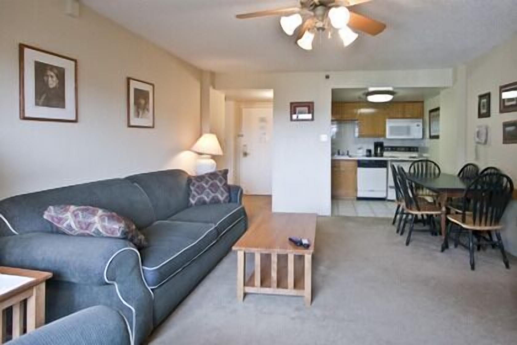 A living room with a sofa, a coffee table, and a dining area with chairs and a table.