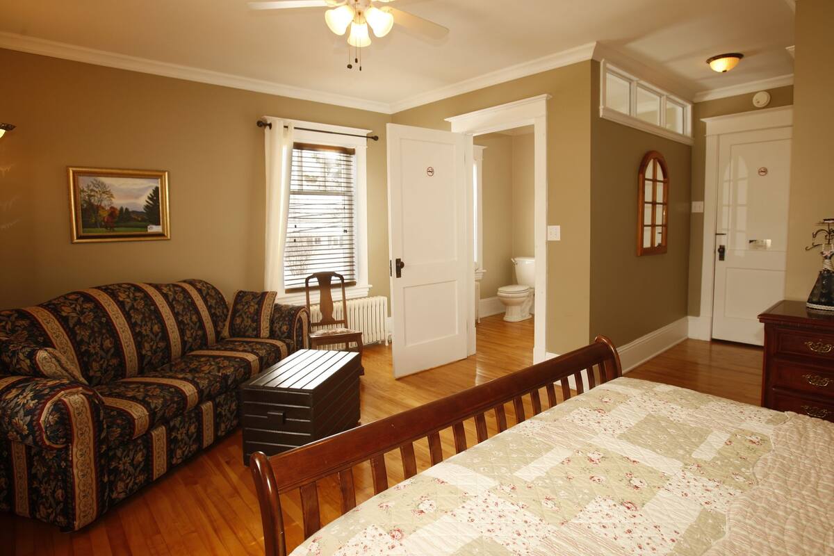 A bedroom with a bed, a sofa, a dresser, and a chair.