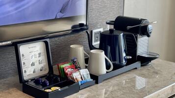 A coffee station with a coffee maker, cups, and a coffee pod holder.