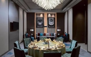 Un comedor moderno con una mesa redonda dispuesta para una comida, rodeada de sillas.