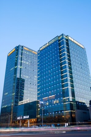 A high-rise building with reflective glass windows and signage for "GREENLAND GROUP" and "MELIA JINAN". - Melia Jinan (Jinan)