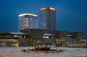 A modern building with a unique lotus-shaped sculpture in the center, surrounded by a spacious plaza. - Melia Jinan (Jinan)