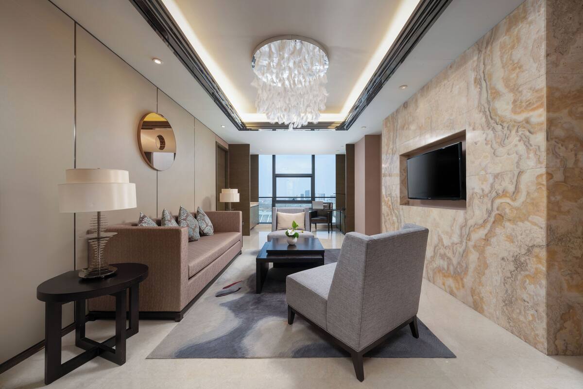 A modern living room with a sofa, armchair, coffee table, and a TV mounted on the wall.