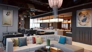 Um hall de hotel moderno com um amplo sofá, área de refeições e um bar.