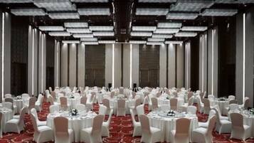 A large banquet hall with round tables and white chairs, arranged in rows.