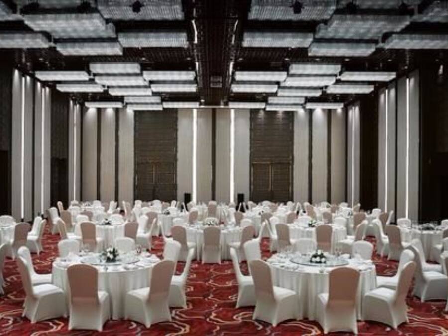 A large banquet hall with round tables and white chairs, arranged in rows.
