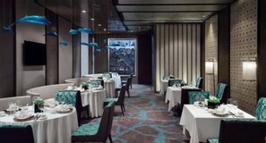 A dining area with round tables, chairs, and a patterned carpet. - Melia Jinan (Jinan)