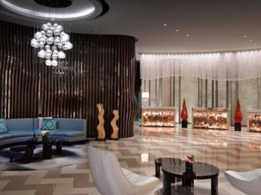 A spacious lobby with a curved sofa, a coffee table, and a decorative chandelier.