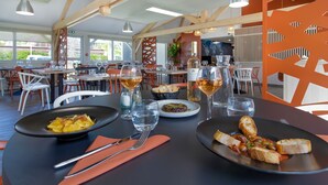 A restaurant with tables set for dining, featuring dishes and glasses of wine.