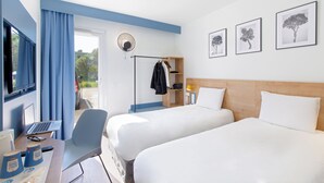A hotel room with two beds, a desk with a laptop, a chair, and a wardrobe.