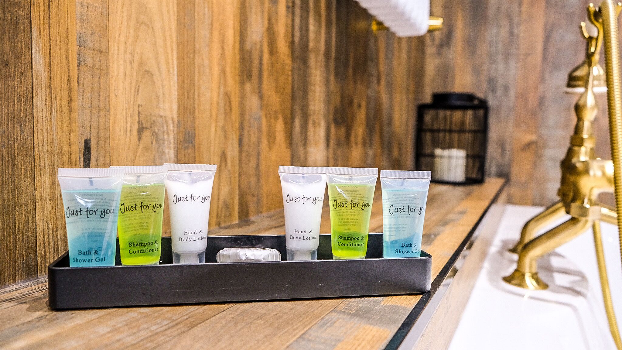 A set of toiletries in a black tray on a wooden counter.