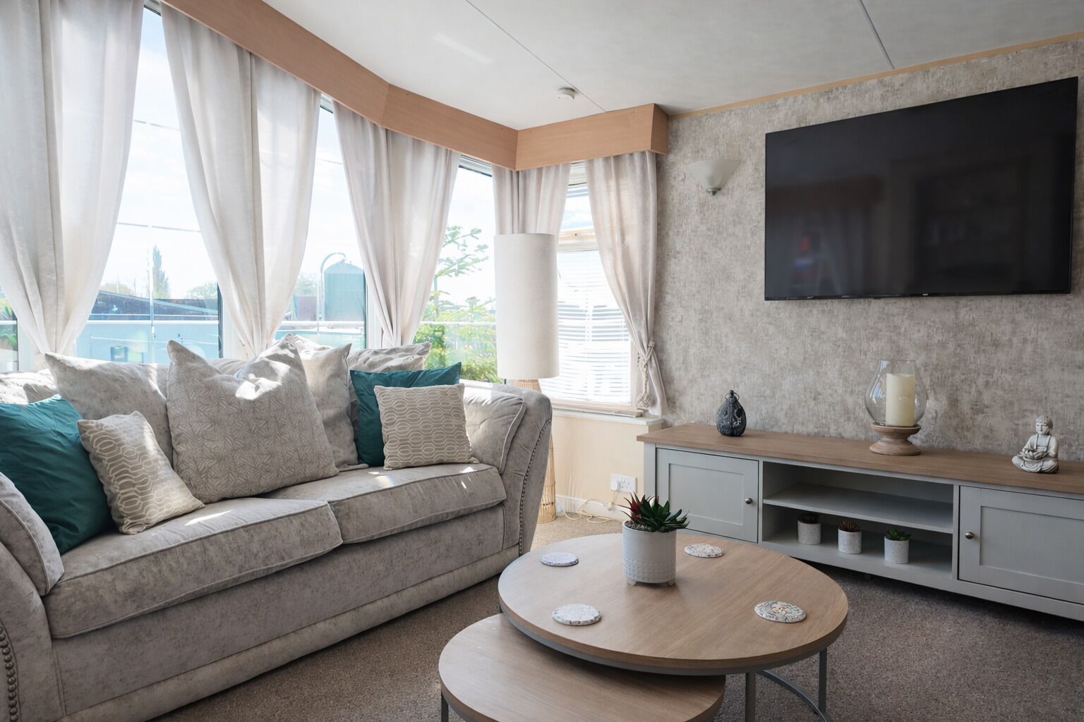A modern living room with a sofa, a coffee table, a TV, and a view of the city.