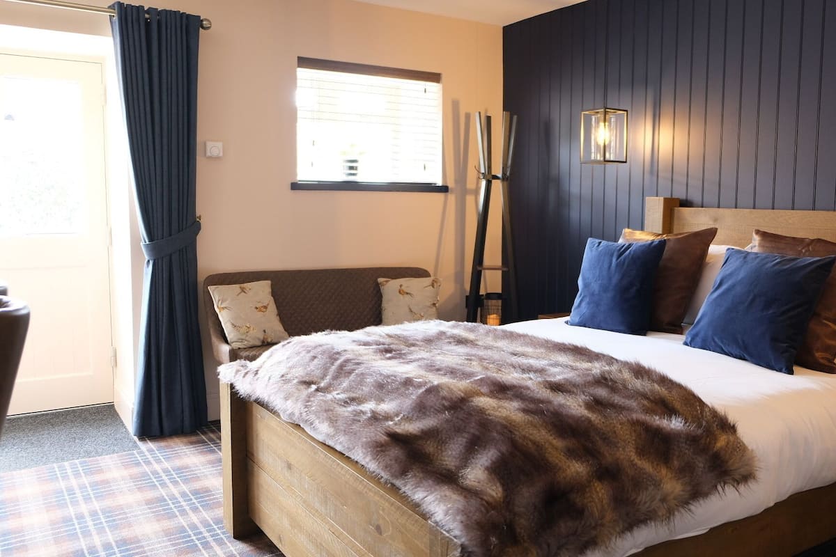 Un dormitorio con una cama de madera, un plaid de piel sintética y una ventana con persianas.