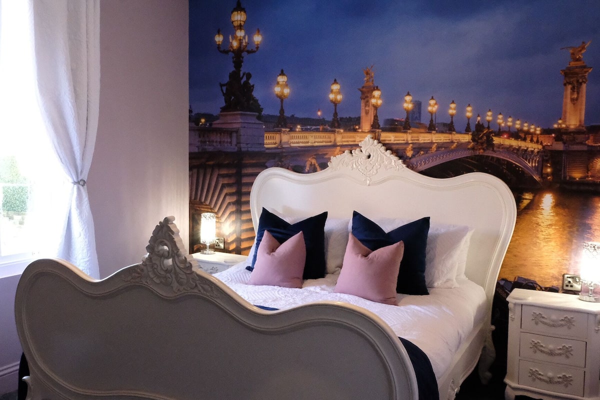 Un dormitorio con cama, mesitas de noche y vista a un puente de noche.