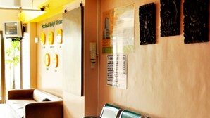 A waiting area with green chairs, a bench, and a wall with artwork and a sign.