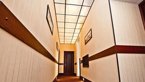 A hotel hallway with a wooden floor, a tiled ceiling, and a door at the end. - Hotel Classic (Kharkiv)