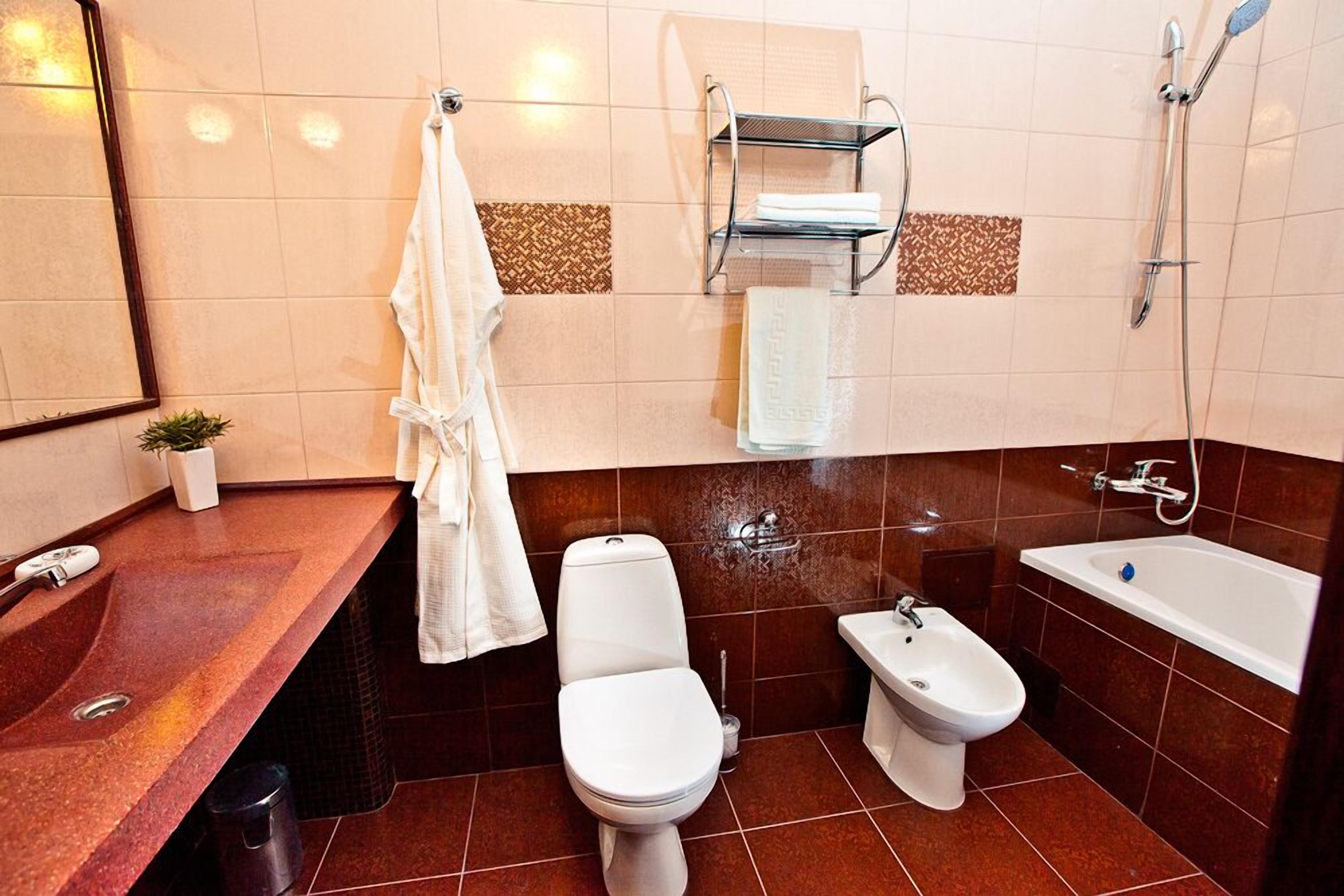 Un bagno moderno con lavandino in marmo, un water, un bidet e una vasca da bagno.