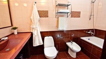 Un bagno moderno con lavandino in marmo, un water, un bidet e una vasca da bagno.
