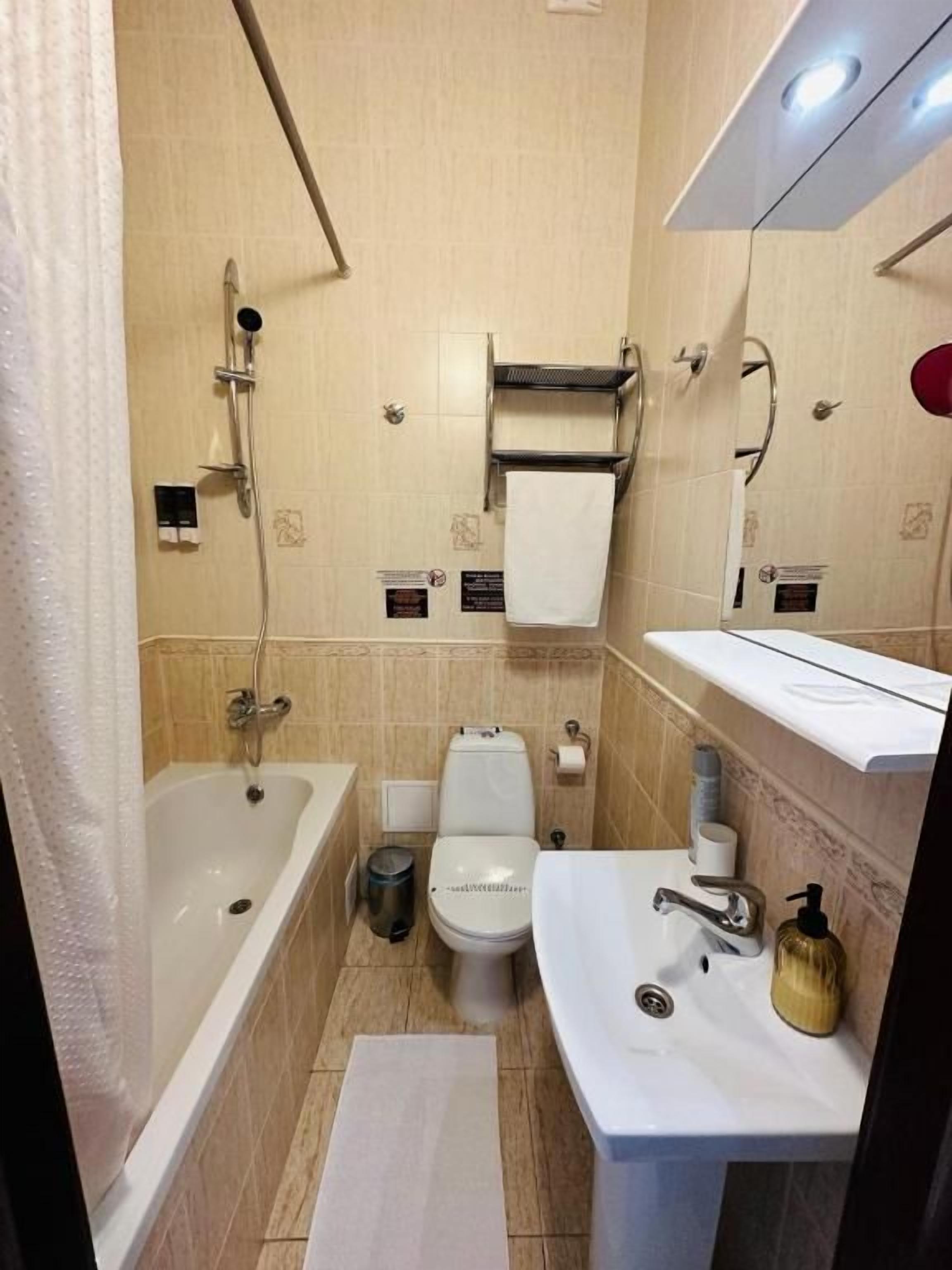 Un baño con bañera, inodoro, lavabo y toallero.