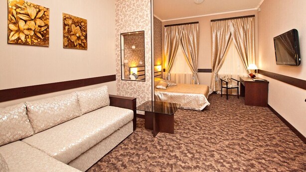 A hotel room with a sofa, a bed, a desk, and two paintings on the wall. - Hotel Classic (Kharkiv)