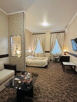 Una habitación de hotel con una cama, un sofá, una mesa de centro, un escritorio y un televisor.