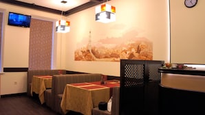 A restaurant with booths, a TV, and a mural of a landscape. - Hotel Classic (Kharkiv)